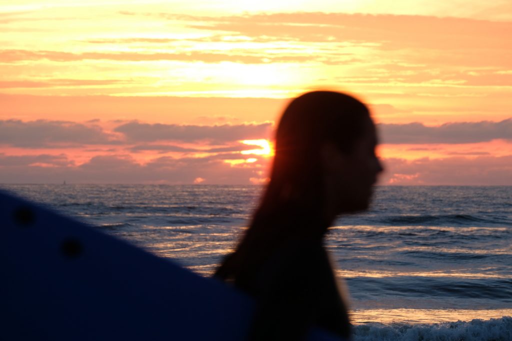 Surfcamp auf Fuerteventura Sonnenuntergang Frau mit Board vor Sonnenuntergang
