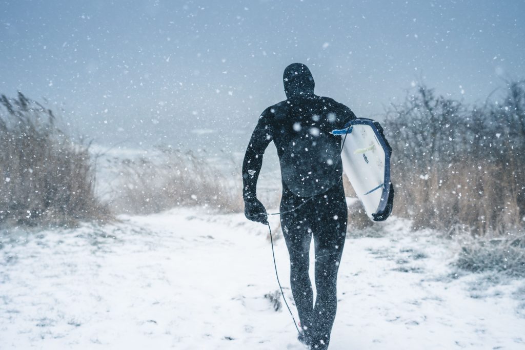 Mann im Schnee mit Neoprenanzug und Board