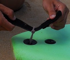 Führe das Ende der Leash, welches du nicht an deinem Unterschenkel befestigst, durch das Leash-Bändchen am Leash-Plug. Führe das Ende der Leash, welches du nicht an deinem Unterschenkel befestigst, durch das Leash-Bändchen am Leash-Plug.