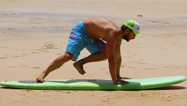 Mit einem Ruck drückst du dich hoch und ziehst das Bein, was noch gestreckt auf deinem Surfboard liegt, nach vorn. Mit einem Ruck drückst du dich hoch und ziehst das Bein, was noch gestreckt auf deinem Surfboard liegt, nach vorn.