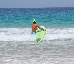 Schleifst du dein Surfboard seitlich neben dir auf dem Wasser entlang, kannst du zudem Kraft für den Transport sparen.
